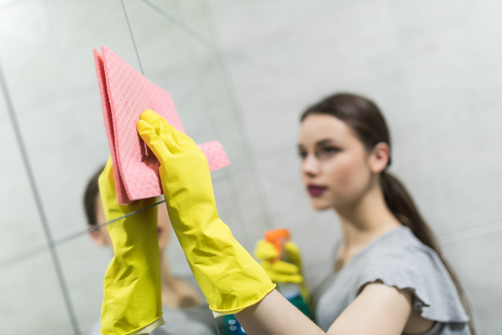 AWomanPolishingMirrorUsingACleaningSpongeAndRubber - welltica.dk - Vejen til et bedre liv