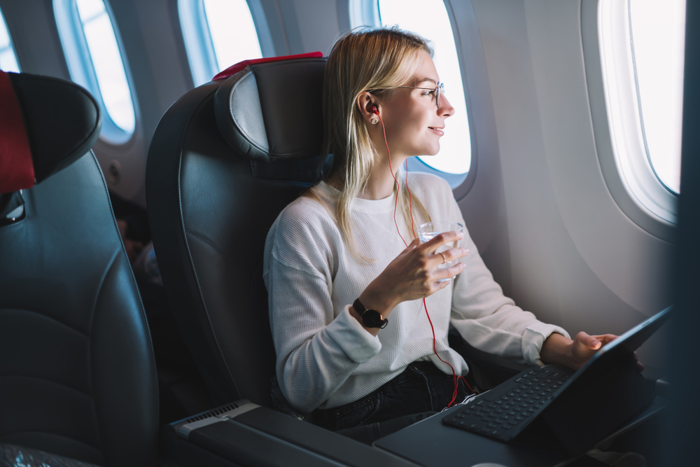 YoungCaucasianSmilingFemaleEnjoyingHerComfortableFlightWhileSitting - welltica.dk - Vejen til et bedre liv