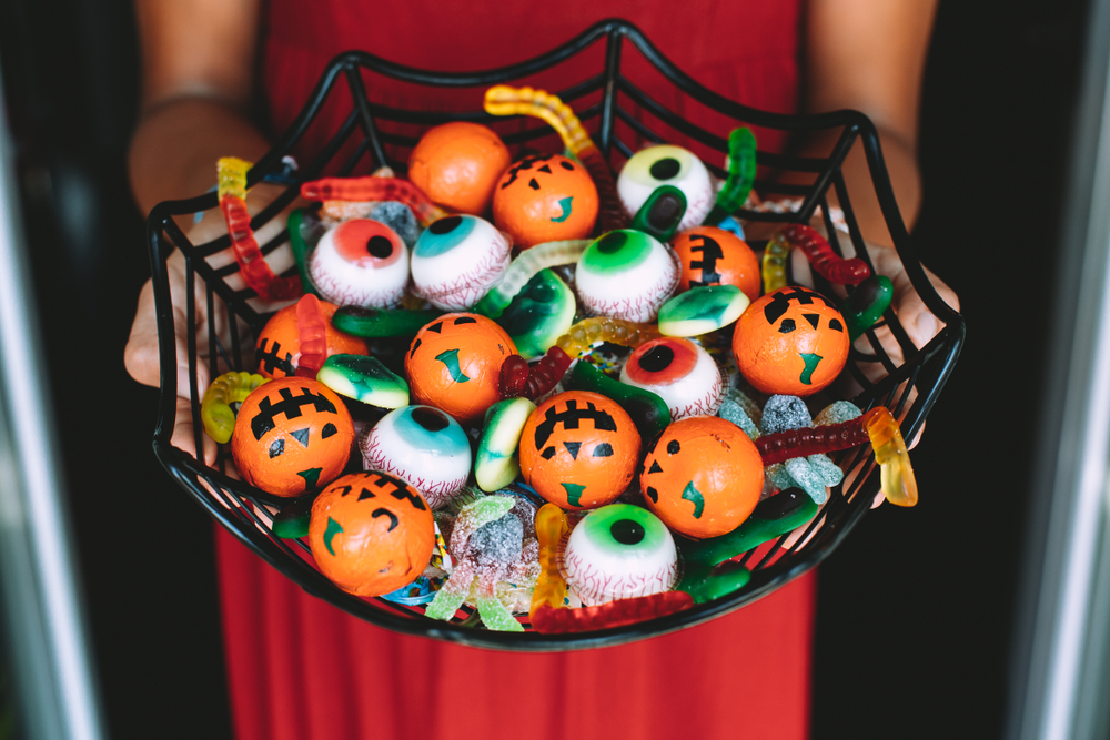 WomanAtTheFrontDoorOfferingFunnyHalloweenCandiesOn - welltica.dk - Vejen til et bedre liv