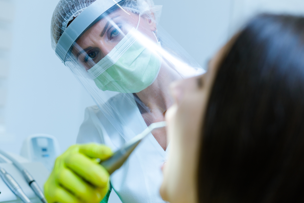 FemaleDentistWearingFaceMaskGlovesAndVisorAsCoronavirus - welltica.dk - Vejen til et bedre liv