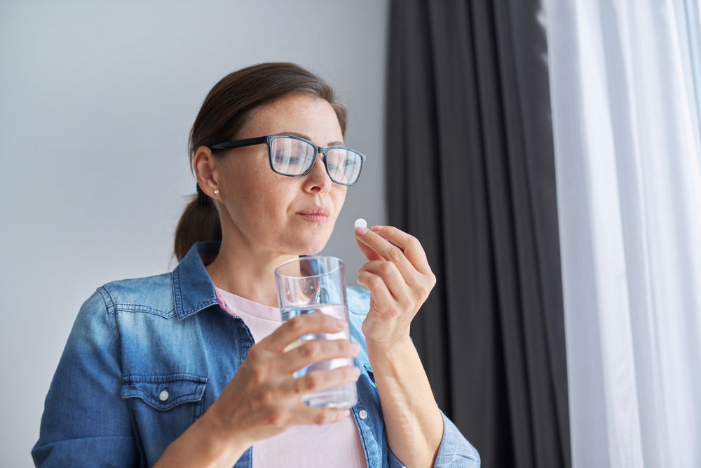 MatureMiddle-agedWomanInCasualClothesAtHomeHoldingPill - welltica.dk - Vejen til et bedre liv