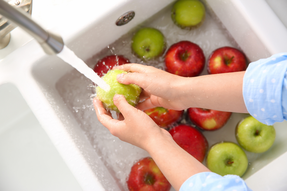 WomanWashingFreshApplesInKitchenSinkTopView - welltica.dk - Vejen til et bedre liv