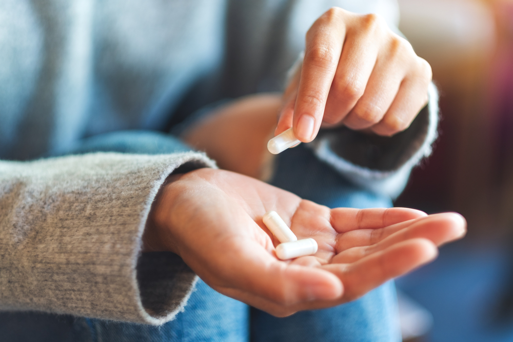 CloseupImageOfAWomanHoldingAndPickingWhiteMedicine - welltica.dk - Vejen til et bedre liv