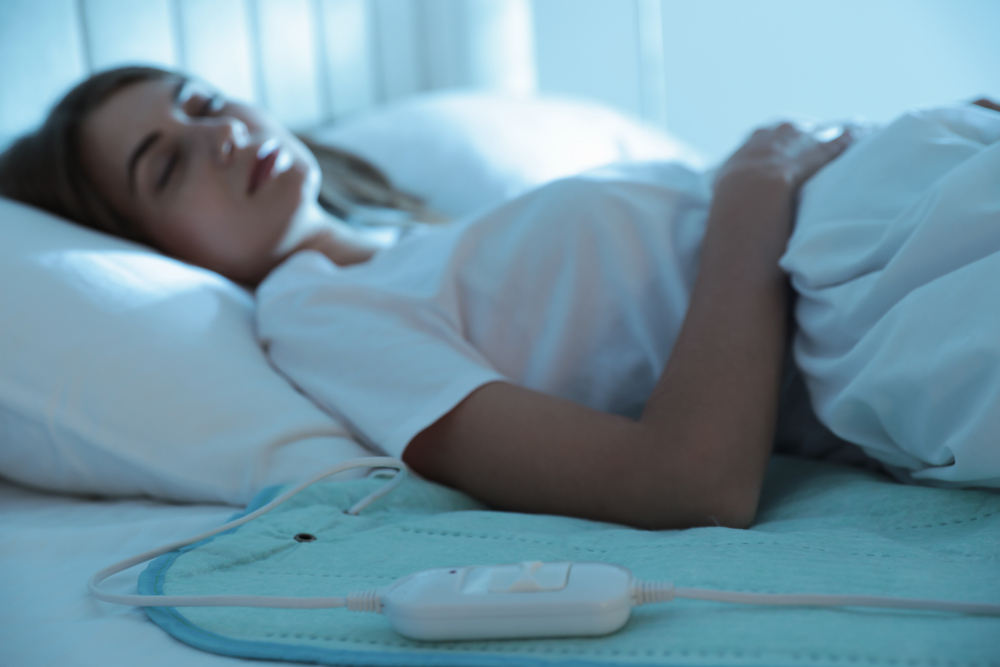 YoungWomanSleepingInBedWithElectricHeatingPadFocus - welltica.dk - Vejen til et bedre liv