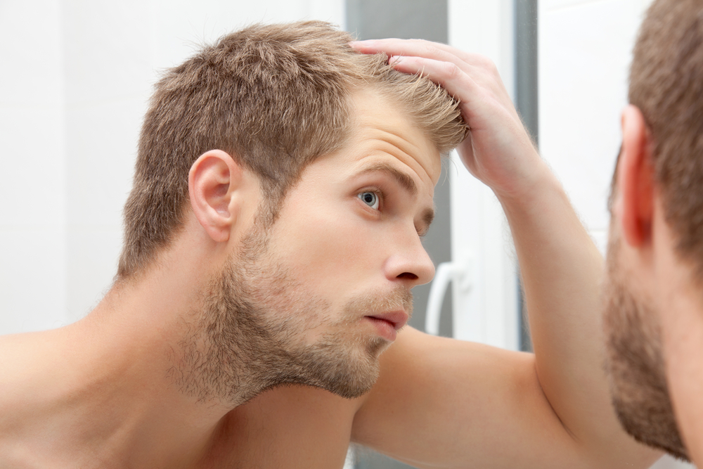 HandsomeUnshavenManLookingIntoTheMirrorInBathroom - welltica.dk - Vejen til et bedre liv
