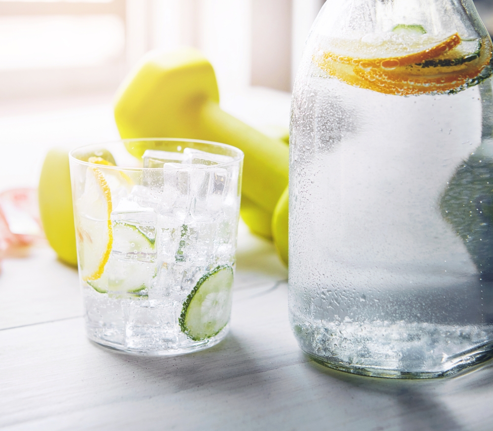 CucumberLemonAndWaterInGlassWithDumbbellOnTable - welltica.dk - Vejen til et bedre liv