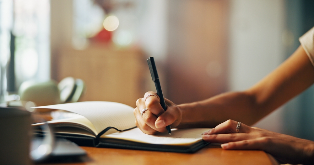 HomePersonAndHandsWithNotebookForWritingScheduleOr - welltica.dk - Vejen til et bedre liv