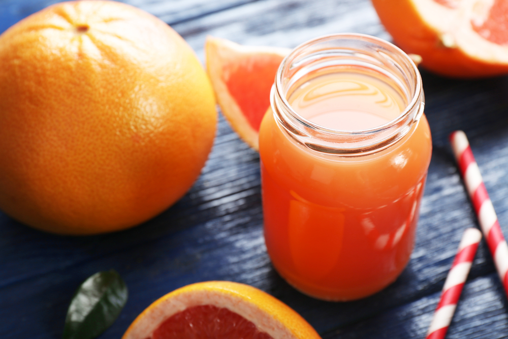 GrapefruitJuiceInBottlesAndFreshFruitsOnDarkBlue - welltica.dk - Vejen til et bedre liv