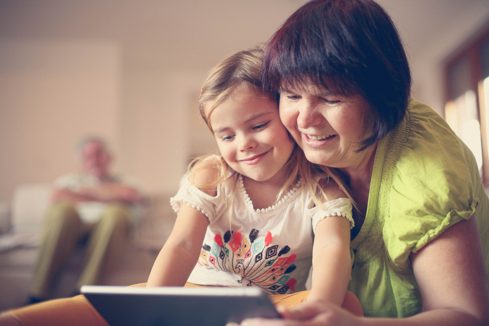 GrandmotherAndGranddaughterLayingOnTheFloorAndUsingTablet - welltica.dk - Vejen til et bedre liv