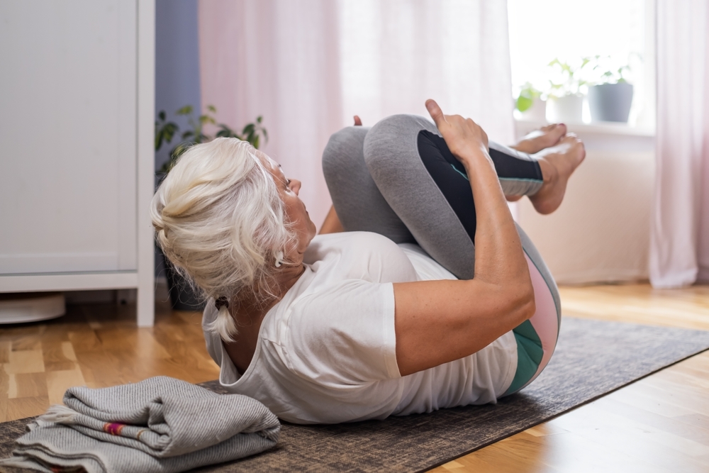 WomanLyingOnYogaMatDoingApanasanaFitFemaleRelaxing - welltica.dk - Vejen til et bedre liv