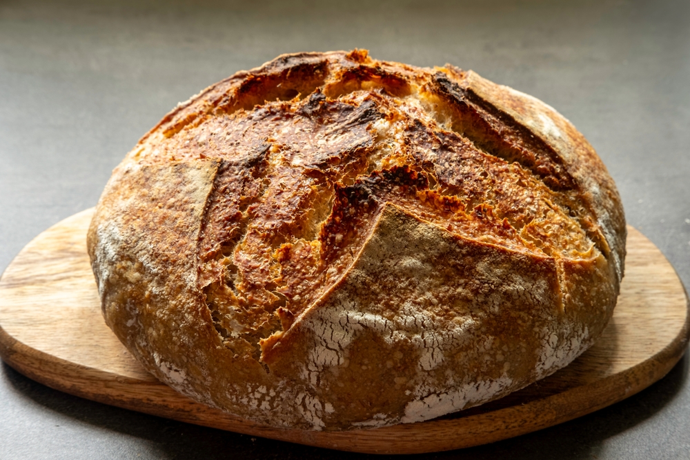 RoundSourdoughBreadCloseUpOnAWoodenBoardOn - welltica.dk - Vejen til et bedre liv