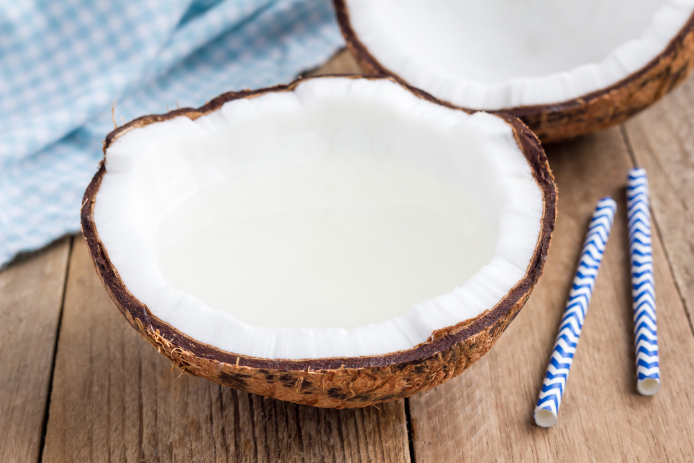 NaturalOrganicCoconutWaterInCrackedCoconutOnWoodenTable - welltica.dk - Vejen til et bedre liv