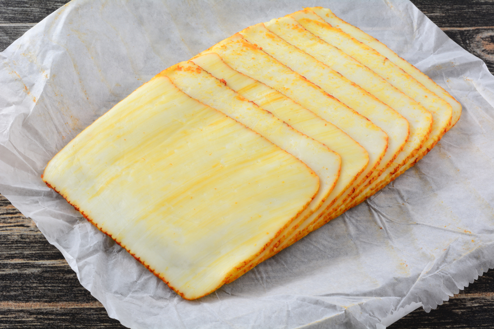 StackOfMuensterCheeseSlicesOnWhitePaperButcherPaper - welltica.dk - Vejen til et bedre liv