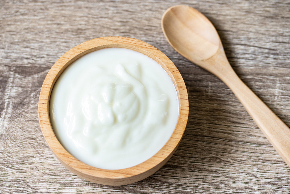 WhiteYogurtInAWoodenCupWithAWoodenSpoon - welltica.dk - Vejen til et bedre liv